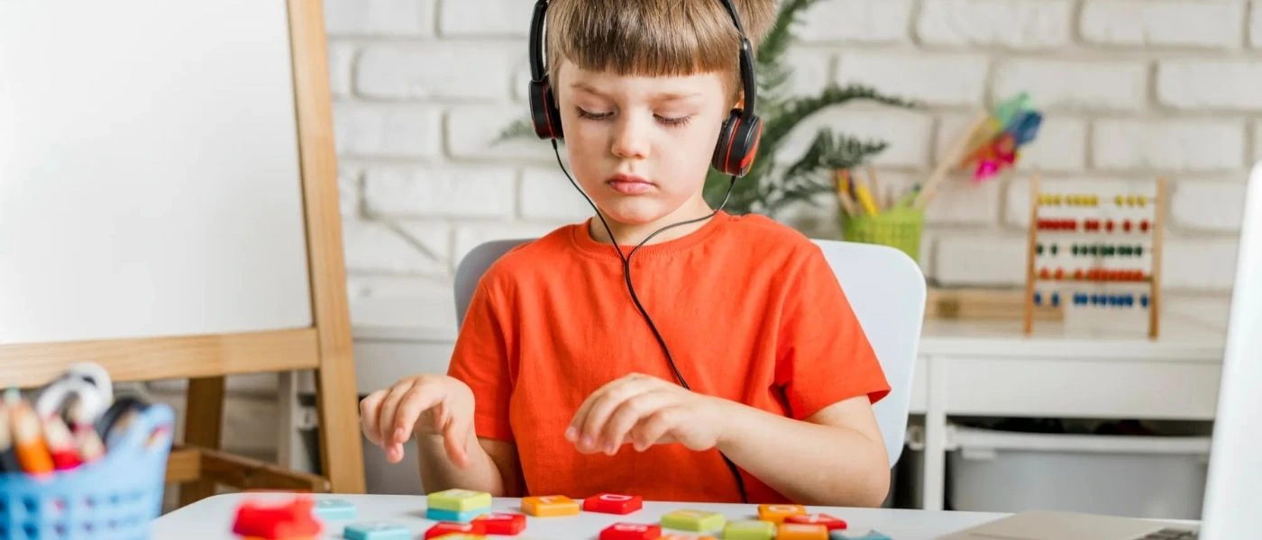 Kind mit Kopfhörern sitzt konzentriert am Tisch – Autismus verstehen bedeutet sensorische Bedürfnisse erkennen