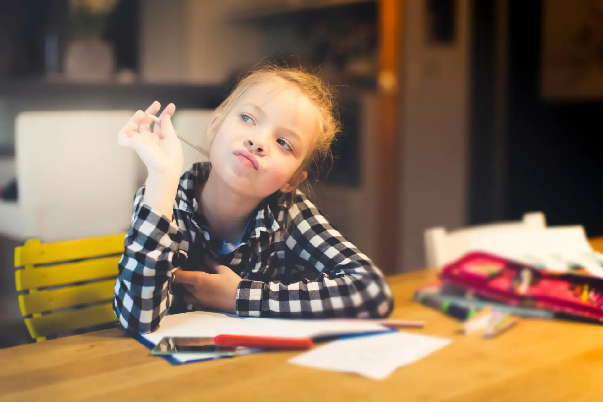 Mädchen schaut am Schreibtisch verträumt zur Seite, ein typisches Bild für AD(H)S bei Kindern